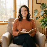 A person sitting in a sunlit armchair holding a notebook and pen with a relieved expression in a warm, professional therapy room with a bookshelf and plants.